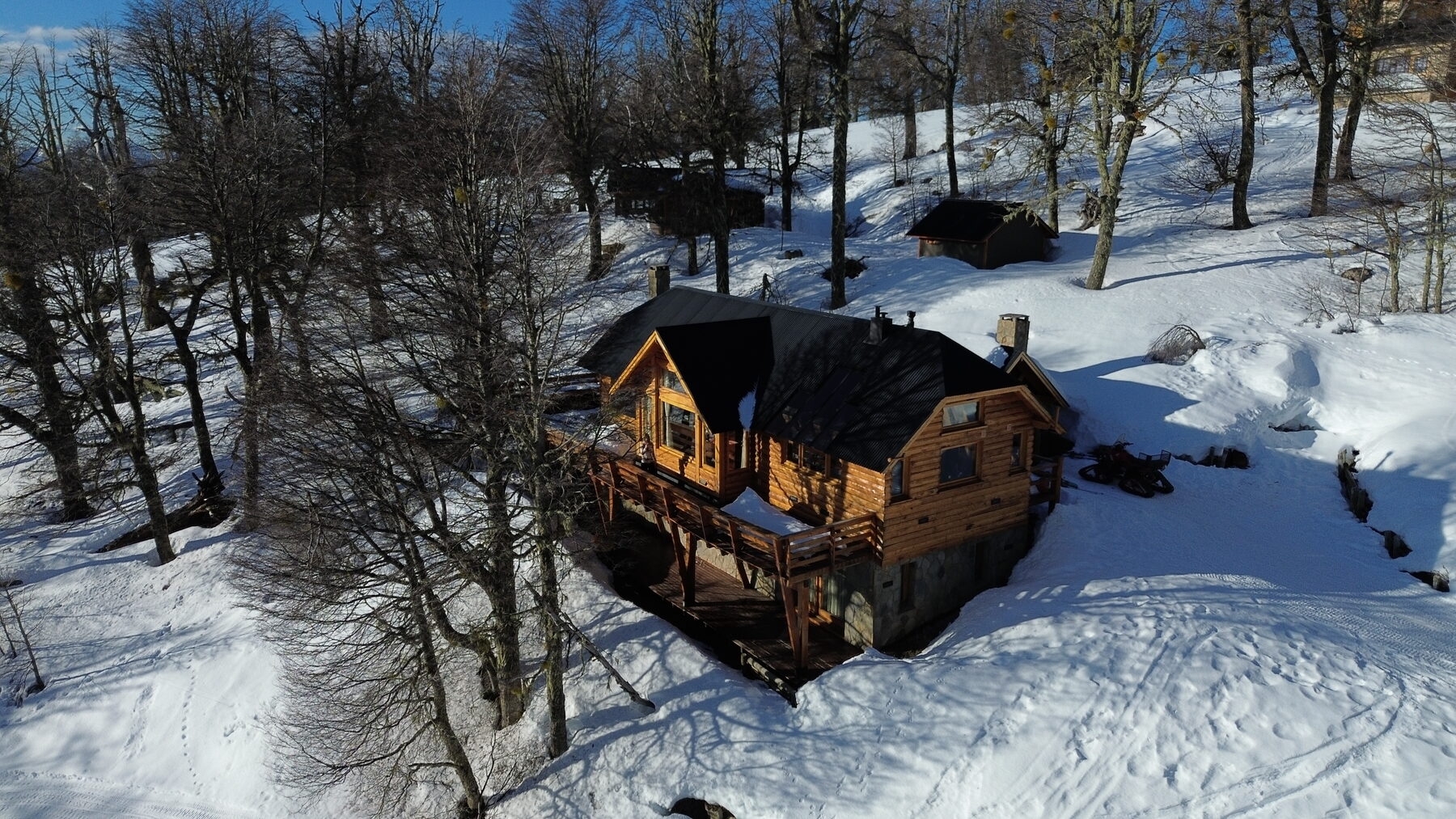 Vista aérea de la cabaña entre el bosque nevado