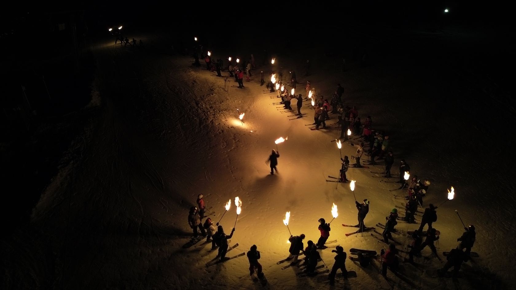 La bajada de antorchas serpenteando por la pista de noche