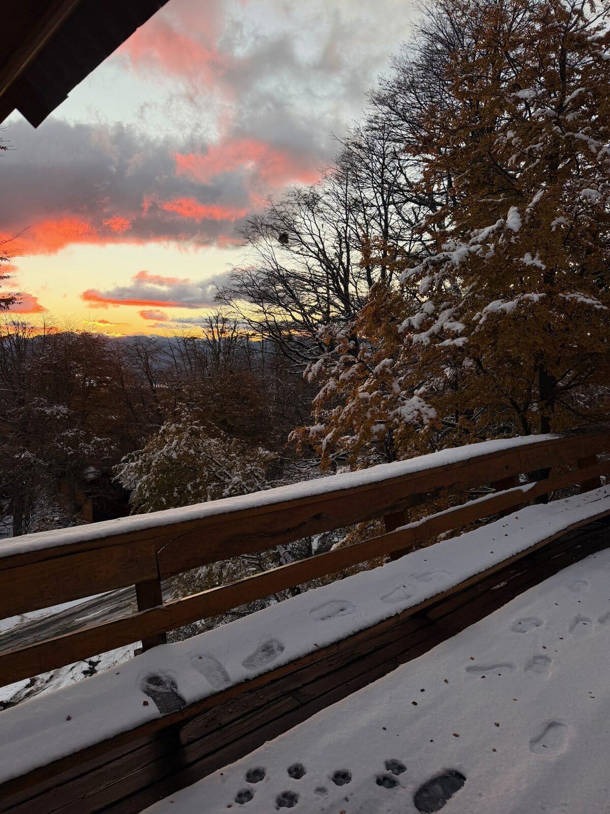El atardecer encendido desde la baranda nevada del deck