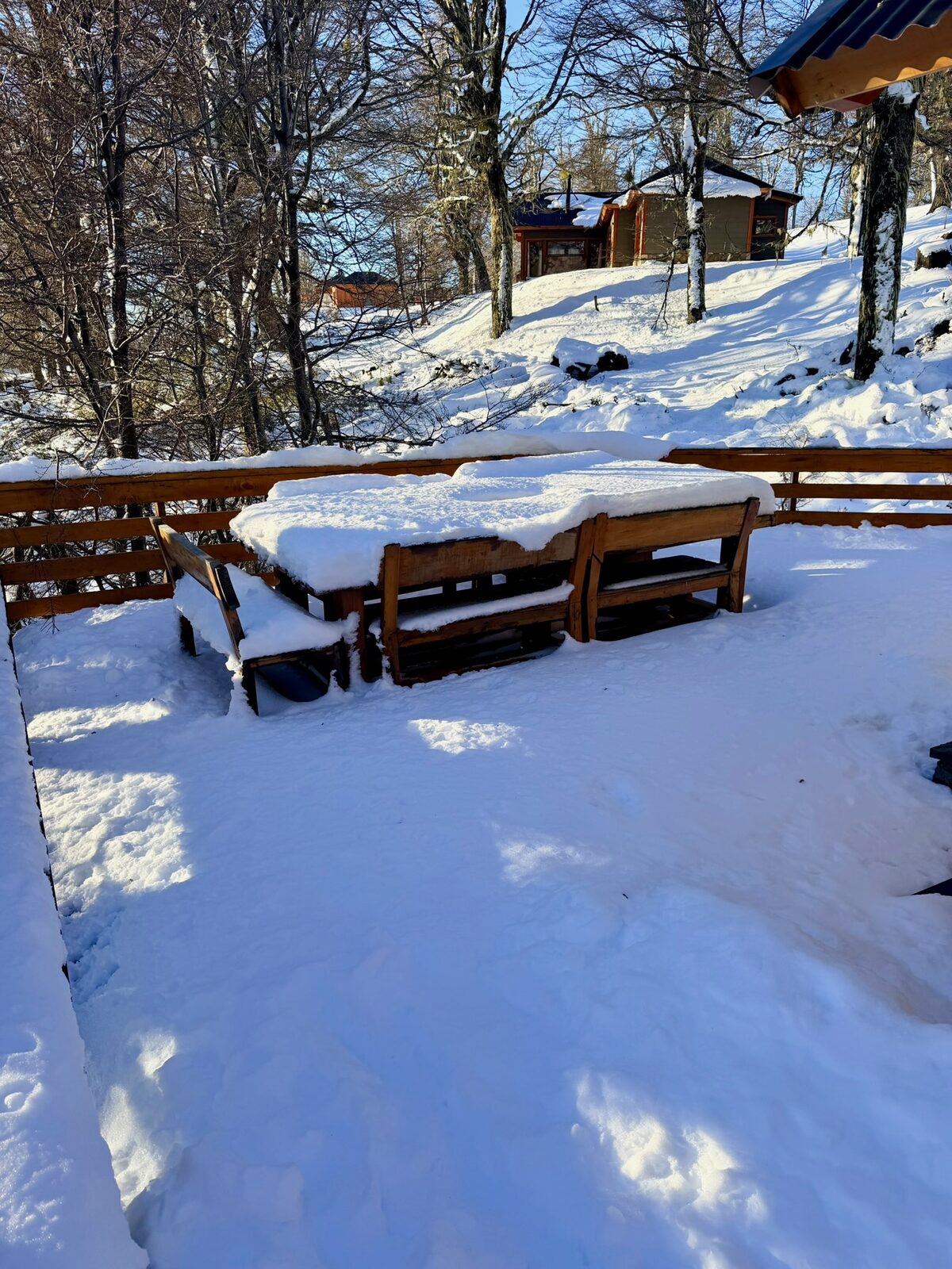 Mesa y bancos del deck nevados en un día de sol