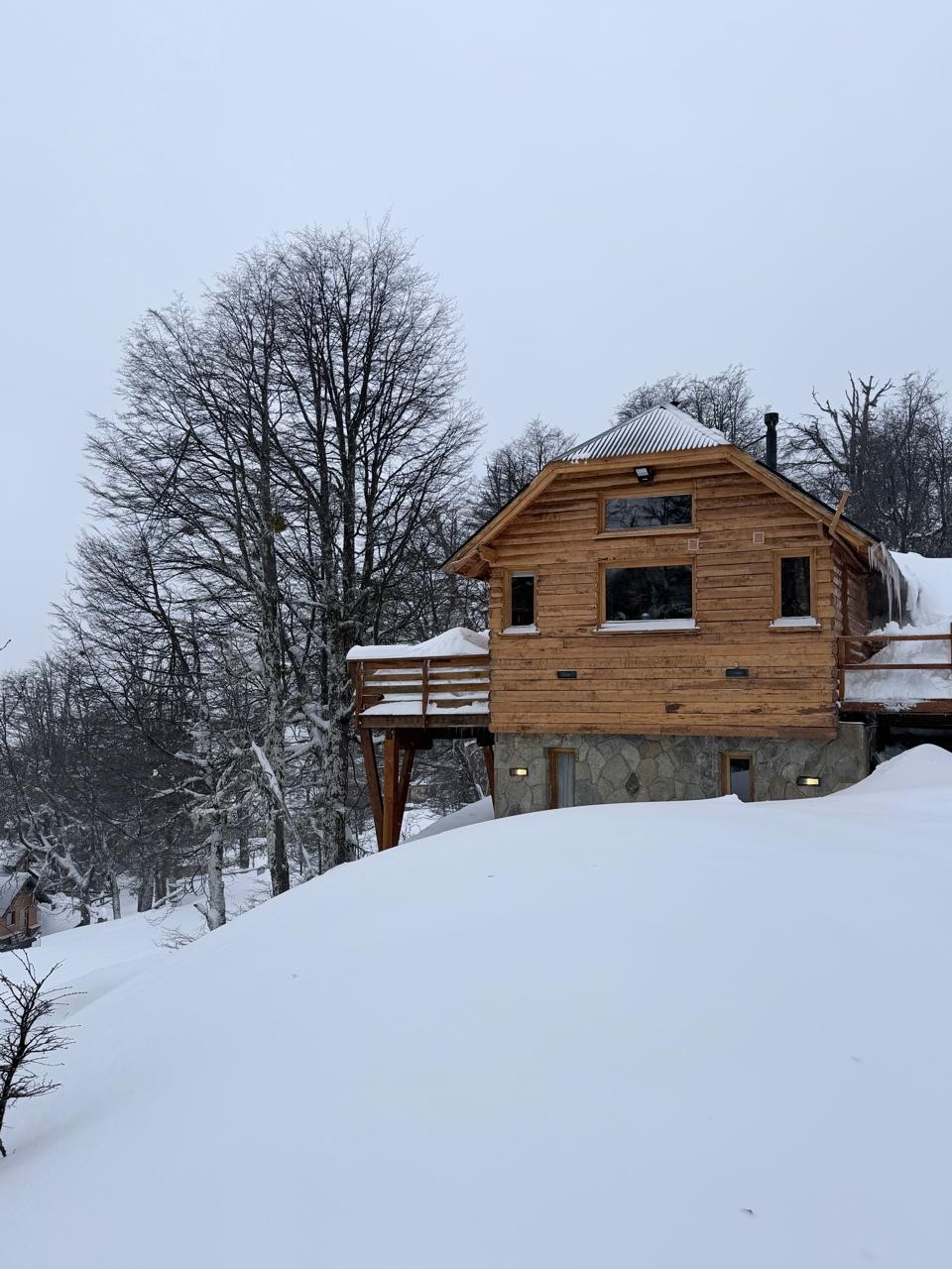 La cabaña y su deck elevado sobre el manto de nieve fresca