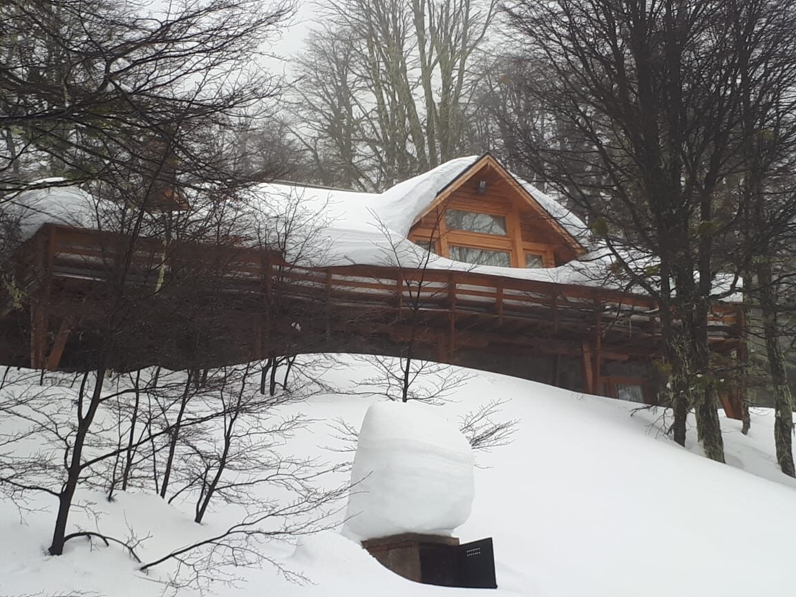La casa vista desde el bosque tras la nevada