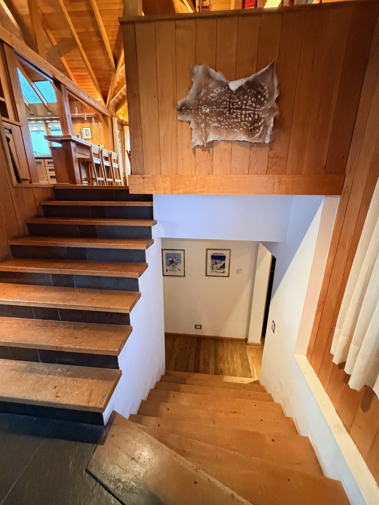 La escalera que baja al pasillo de las habitaciones, con el cuero de ciervo en la pared
