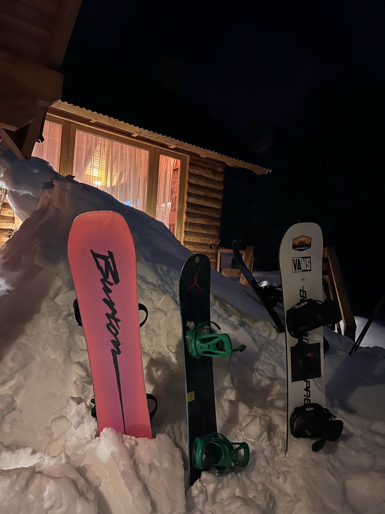 Las tablas clavadas en la nieve al final del día, con la casa iluminada de noche