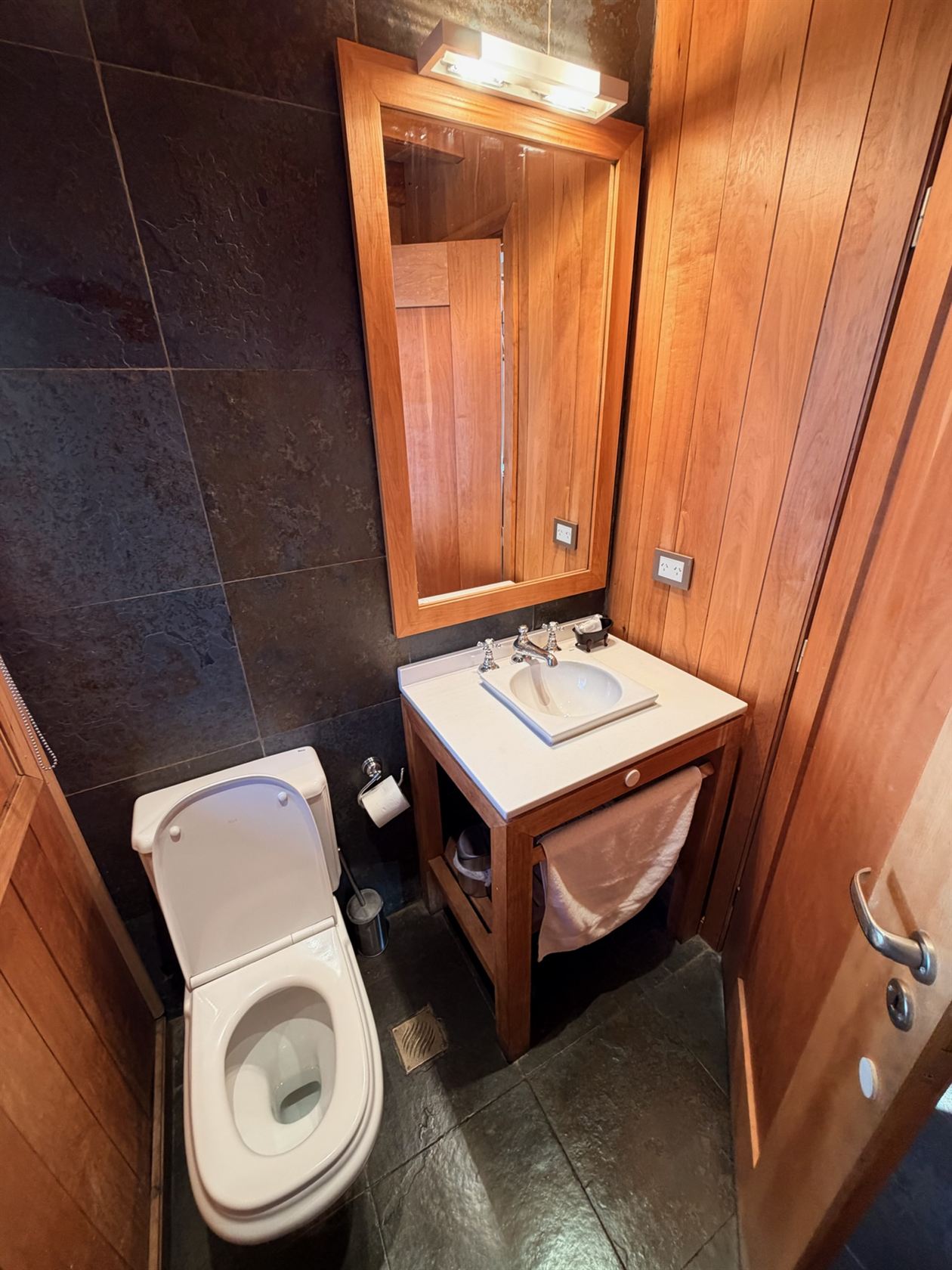 El toilette, con su vanitory de madera y la pared de piedra